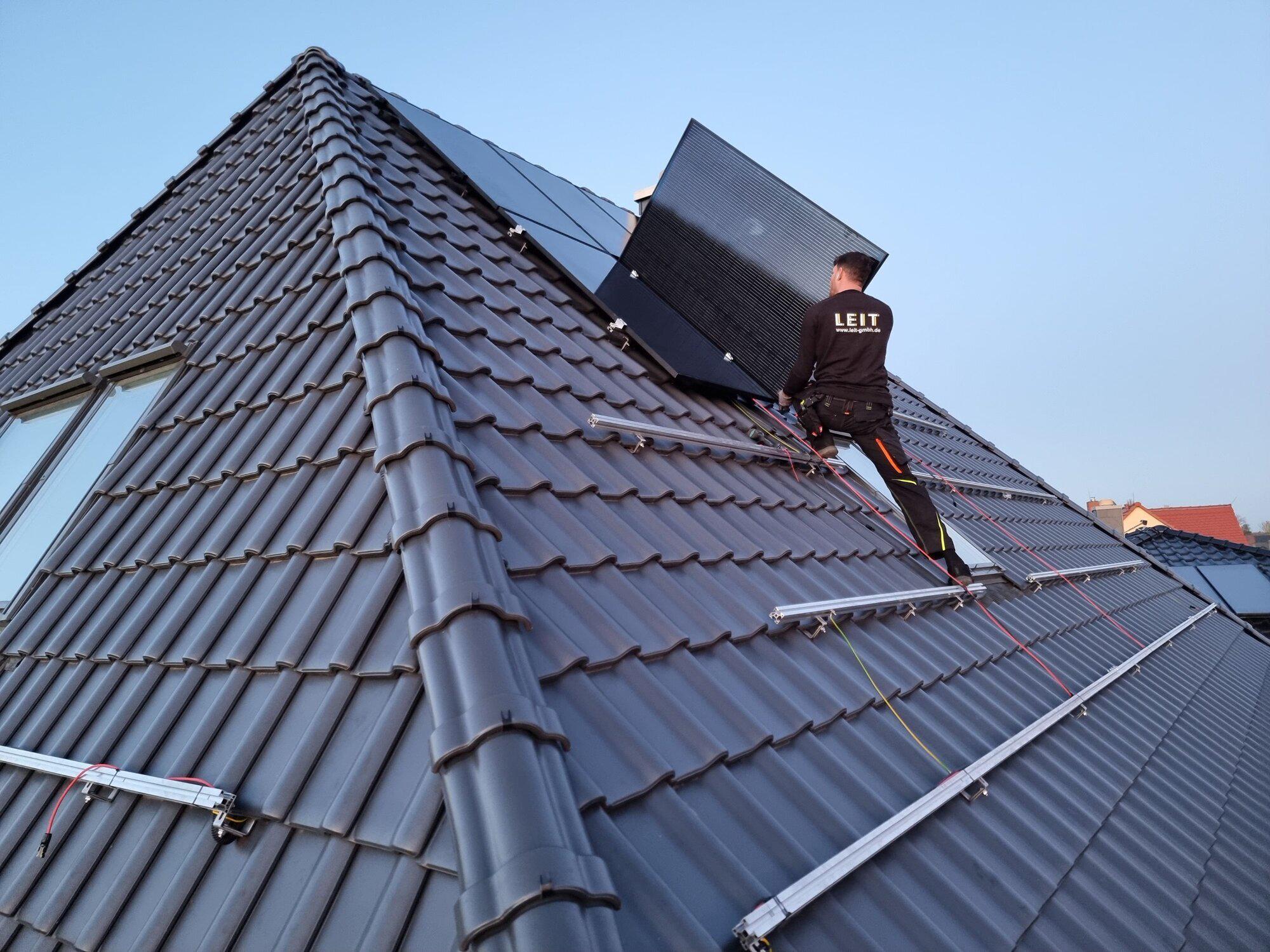 Technician handling a solar panel during rooftop installation